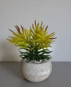 Artificial plant in a decorative pot on a plain background