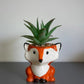 Ceramic fox planter with a succulent on a gray surface