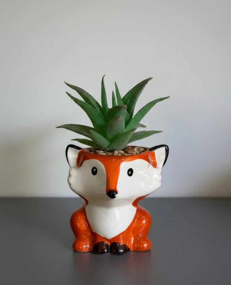 Ceramic fox planter with a succulent on a gray surface