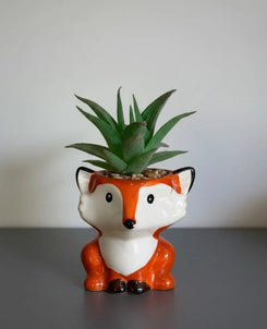 Ceramic fox planter with a succulent on a gray surface