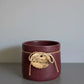 Maroon ceramic cup with a string label on a gray surface and light gray background