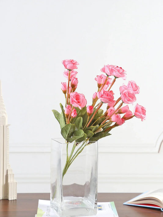 Clear glass vase with pink flowers on a wooden surface with a white background