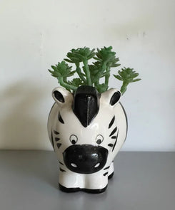 Zebra-shaped planter with a green plant on a plain background